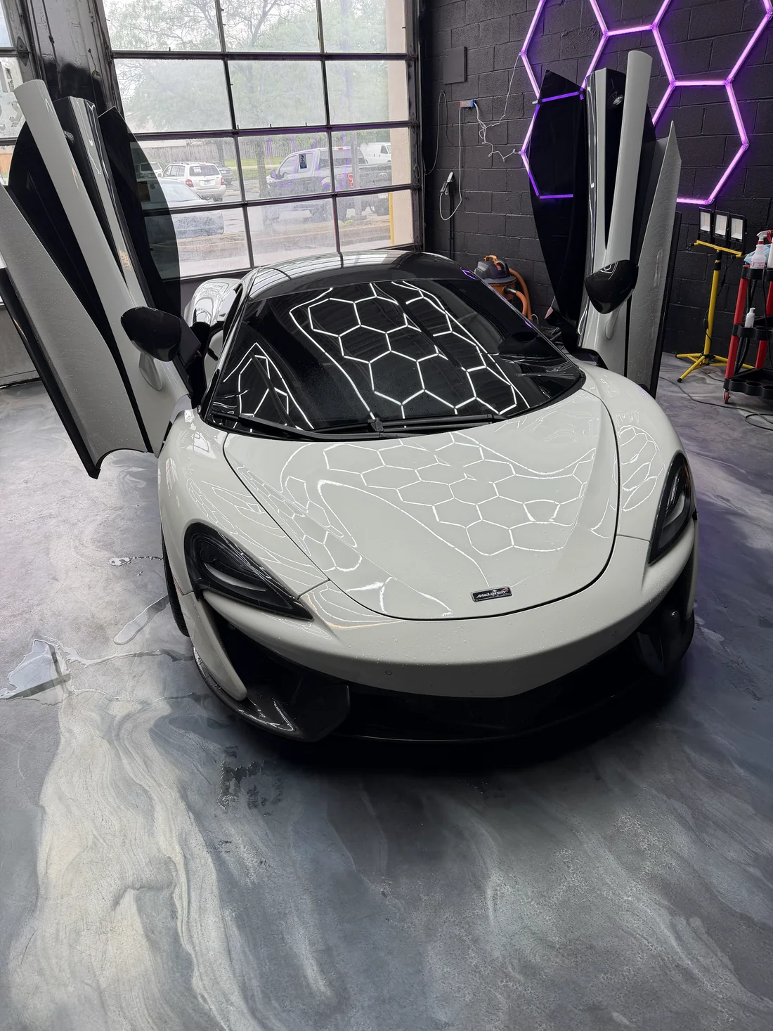 White McLaren with raised doors inside the detailing studio