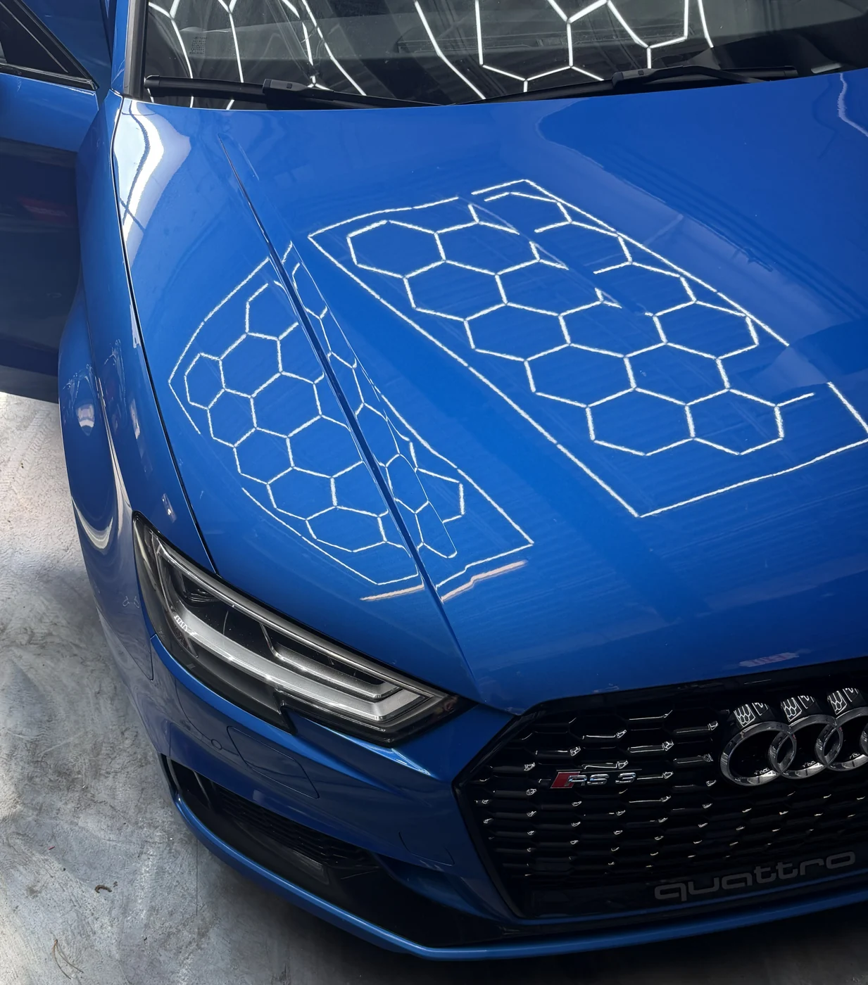 Blue Audi with overhead lights reflected in its paint